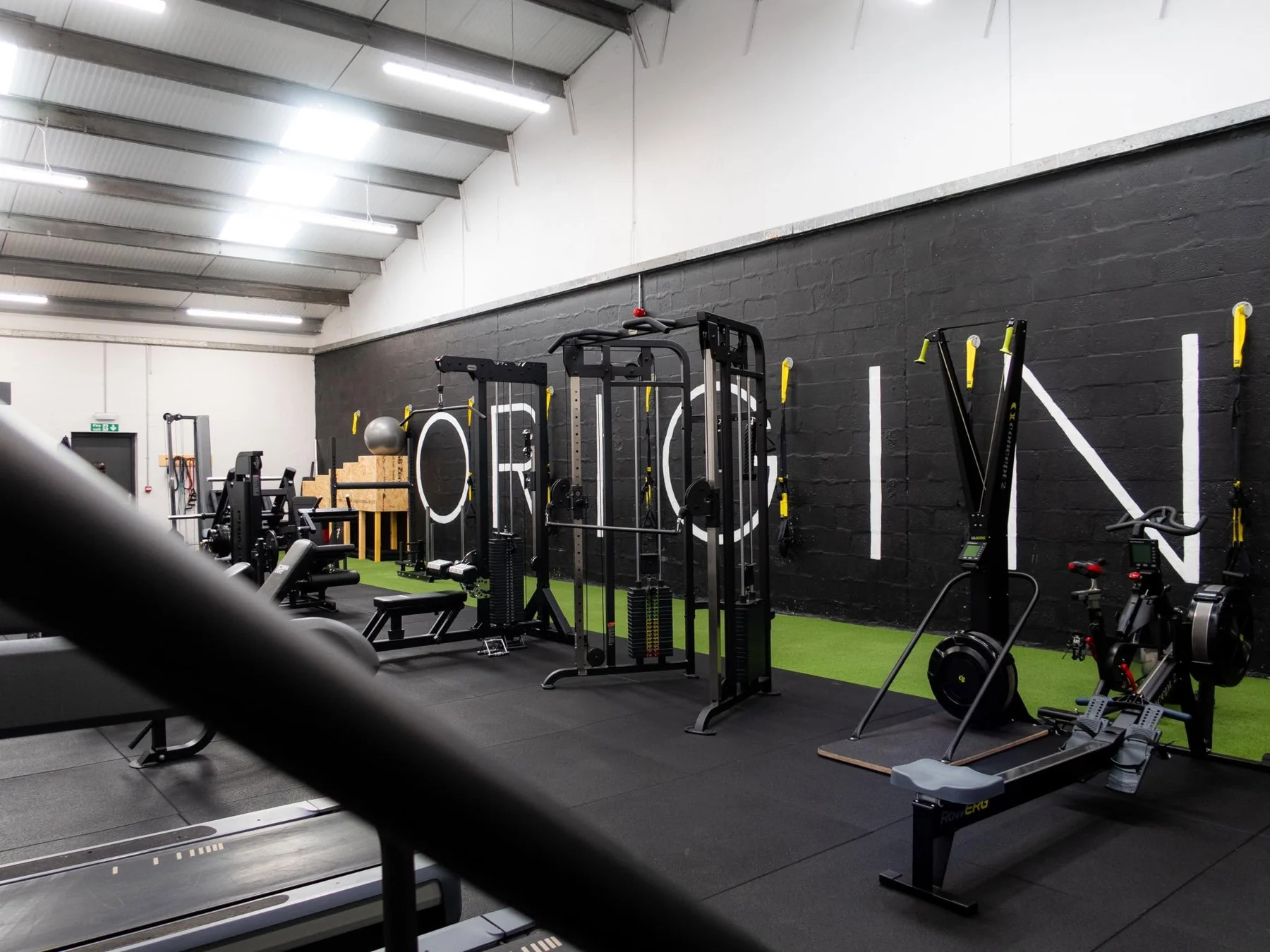 Inside Origin gym, with strength equipment, rowing machines and green turf